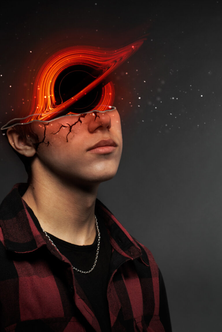 This photo depicts a man with half his face cut off, sliced just below his eyes. Coming out of his head is a black hole with red and orange colours. He is also wearing a red flannel and stars around the top of his head.