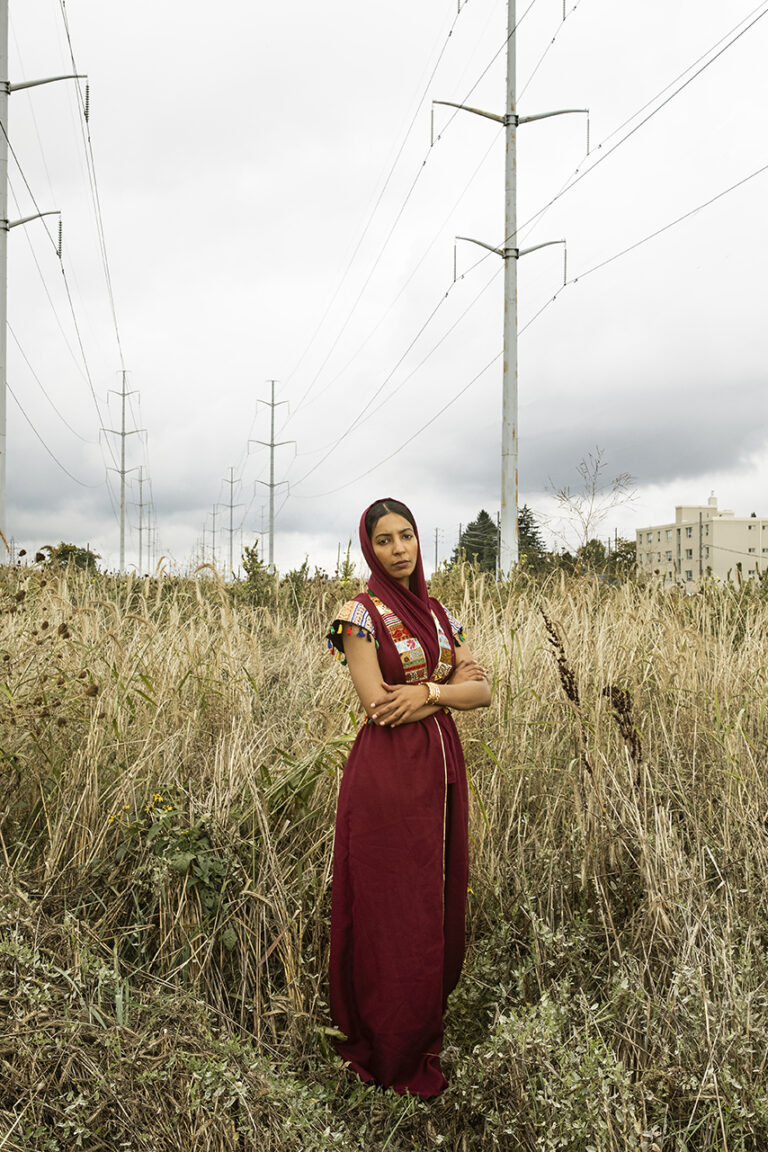 For Huda: a girl standing in the middle of the field wearing a red traditional dress.