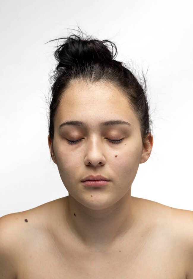 A portrait of a woman with her eyes closed, yarn flows from her eyes to the bottom of the photograph