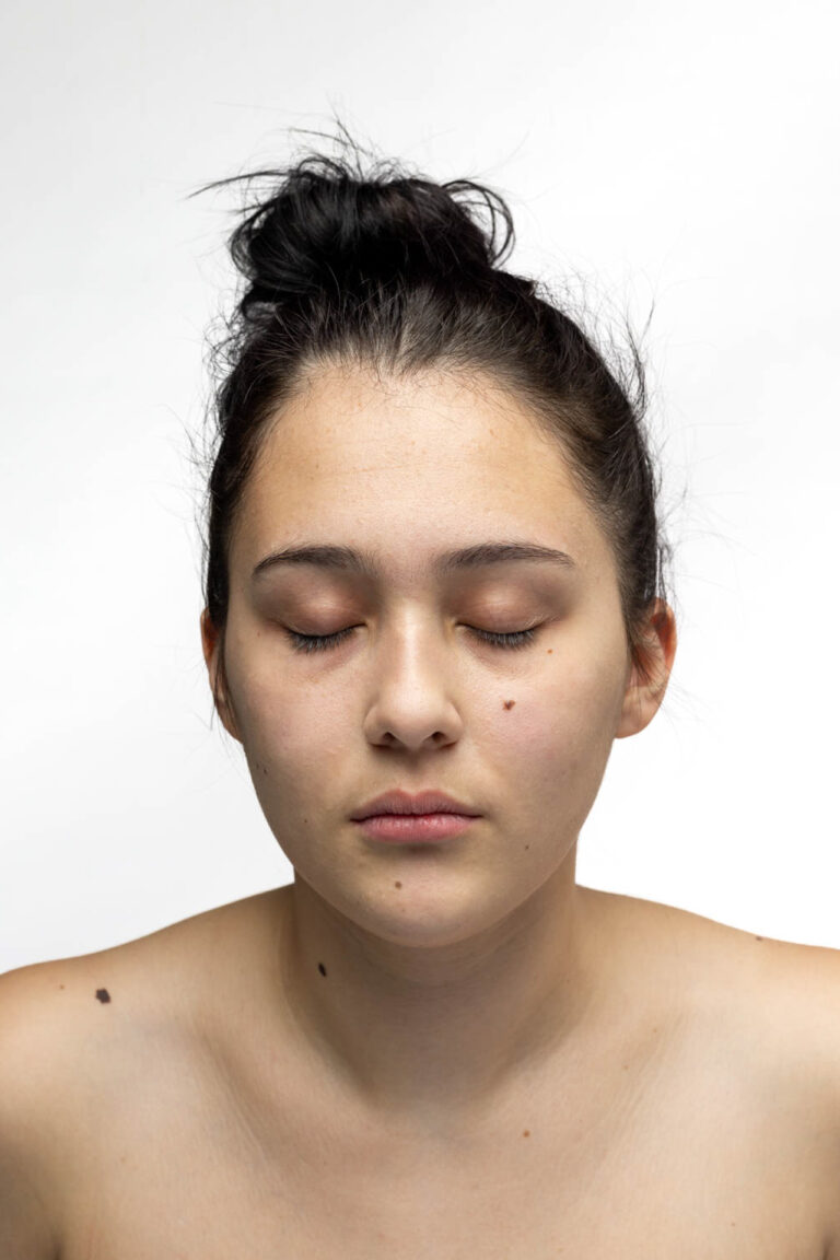 A portrait of a woman with her eyes closed, yarn flows from her eyes to the bottom of the photograph
