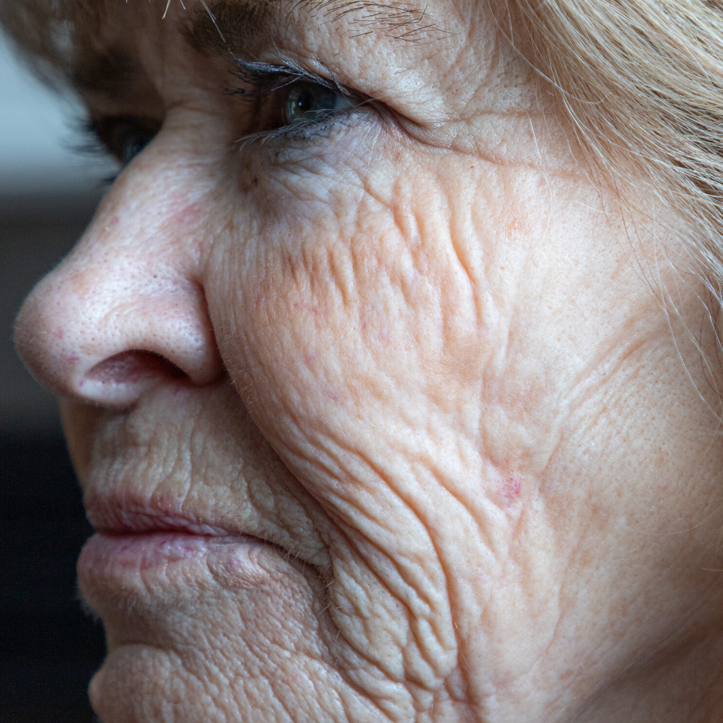 A close up of a person's profile of their face, a strong emphasis on their wrinkles and various textures of their face