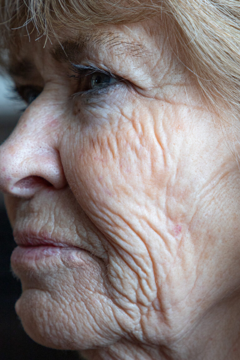A close up of a person's profile of their face, a strong emphasis on their wrinkles and various textures of their face