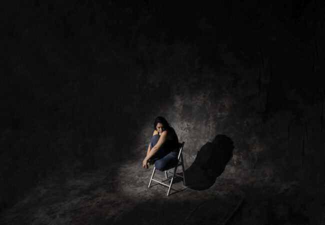 Person on a chair surrounded by darkness