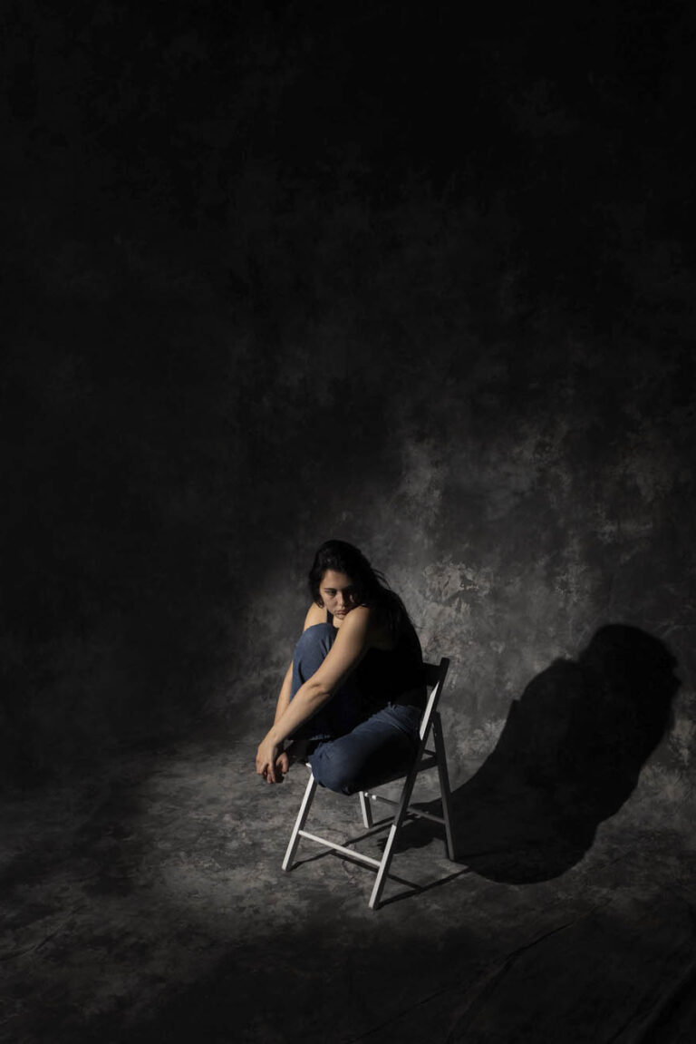 Person on a chair surrounded by darkness