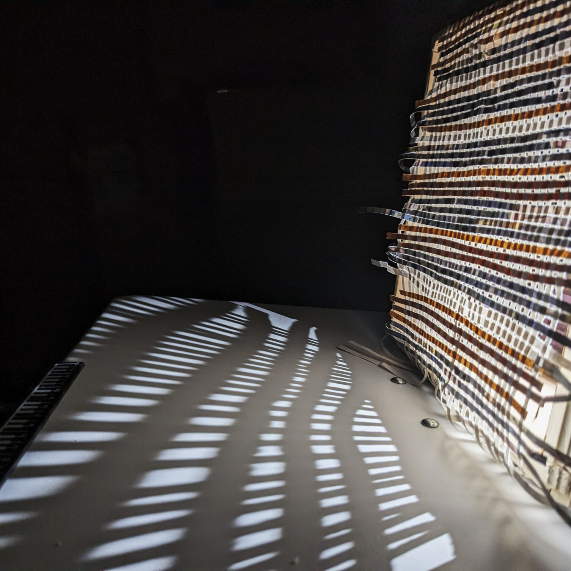 This image is a close up of what happens when a rather weak source of light is projected through the mesh created by weaving strips of recycled paper.