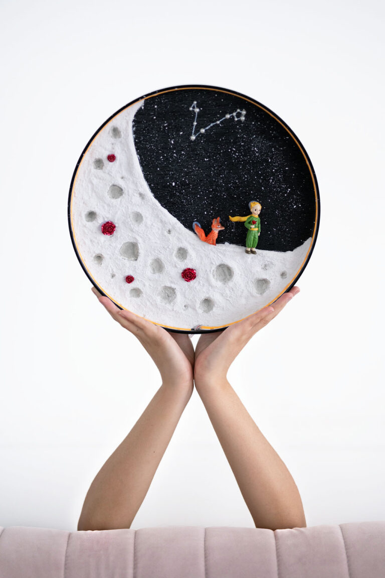 TWO ARMS PROPPED UP WITH HANDS HOLDING A ROUND OBJECT.